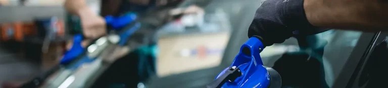 Accueil 24 Technicien SOS Pare-Brise+ remplaçant un pare-brise à domicile devant le garage d'un particulier